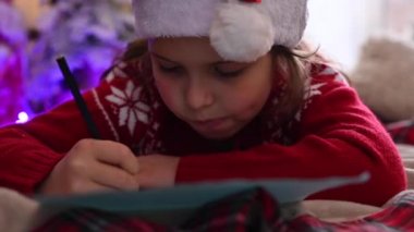 Tatlı çocuk Noel Baba 'ya bir mektup yazıyor, Noel için süslenmiş, Noel ruhuna, bayramlara ve kutlamalara hazırlanıyor.