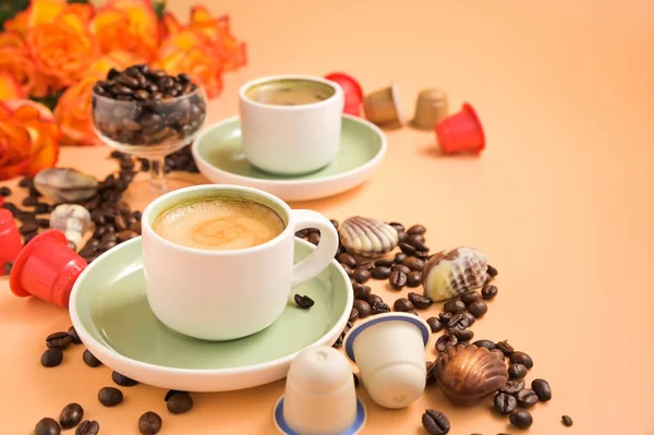 Кофе, шоколад, кофейные зерна и цветы. Эспрессо с пеной или макиато в маленьких чашках — стоковое фото