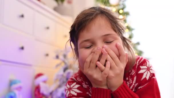 Porträt eines kleinen glücklichen Mädchens zu Weihnachten. Ein Kind europäischen Aussehens lächelt, lacht und in einem Raum, der für die Neujahrsfeiertage dekoriert ist. — Stockvideo