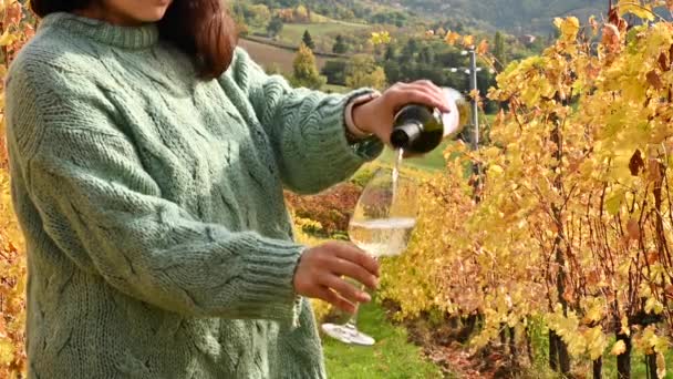 Bottle and glass of wine in female hands. Person pours wineglass a in the hills of italy. Golden vineyards in autumn. Italy. Tuscany