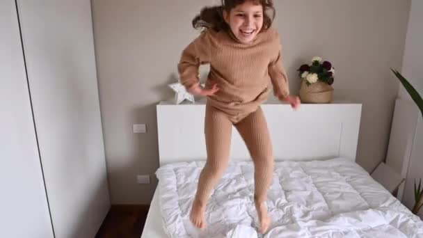 Niña bailando y divirtiéndose en la habitación en la cama — Vídeo de stock