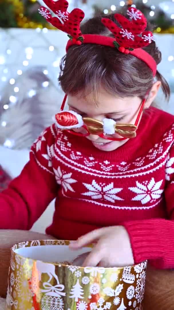 Porträt Weihnachtsmädchen. Ein kleines Mädchen eröffnet eine Überraschung mit einer Weihnachtskugel. Gefühle des Glücks und der Freude. — Stockvideo