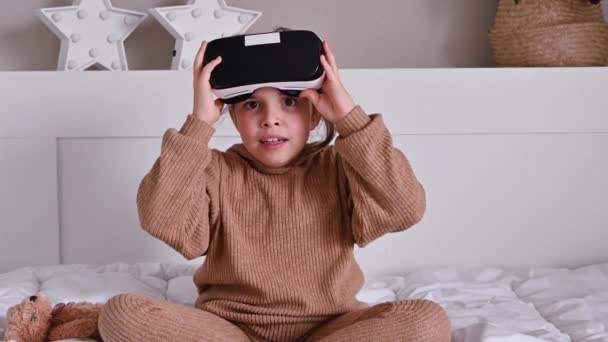 Slim klein meisje dragen Augmented Reality Headset Speelt .she installeert het spel, 3D bril, het concept van moderne games voor kinderen en volwassenen — Stockvideo