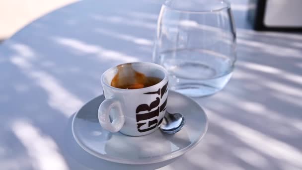 Espresso coffee natural light. A cup of aromatic coffee with froth in the sun and shade — Stock Video