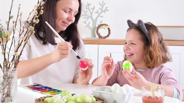 A menina e a mãe pintam ovos para a Páscoa. Criança de aparência europeia — Vídeo de Stock