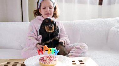 Küçük siyah Cocker Spaniel, sahibinin doğum gününü kutluyor. Evcil hayvan ve tatlı için tatil ve mumlarla mutlu bir kelime..