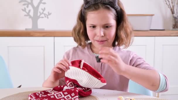 Een klein meisje schildert eieren voor Pasen. Kind schooljongen van Europees uiterlijk en paaseieren, decor op tafel. Lichte binnenkant en natuurlijke opnamen. — Stockvideo