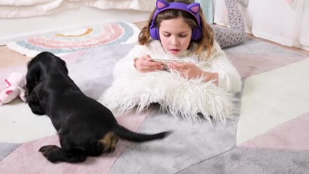 Linda niña sosteniendo un teléfono inteligente, disfrutando de aplicaciones móviles, jugando en la sala de niños. — Vídeos de Stock