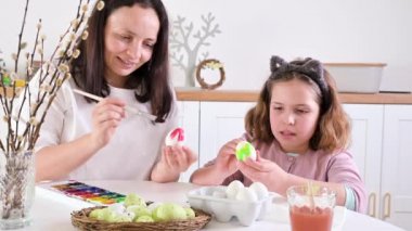 Küçük kız ve anne Paskalya için yumurta boyuyor. Avrupa görünümlü çocuk