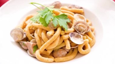 Beyaz bir tabakta sıcak buharlı Vongole makarna. Geleneksel İtalyan restoranında taze öğle yemeği. İstiridye ve maydanozlu makarna. Yakın plan..