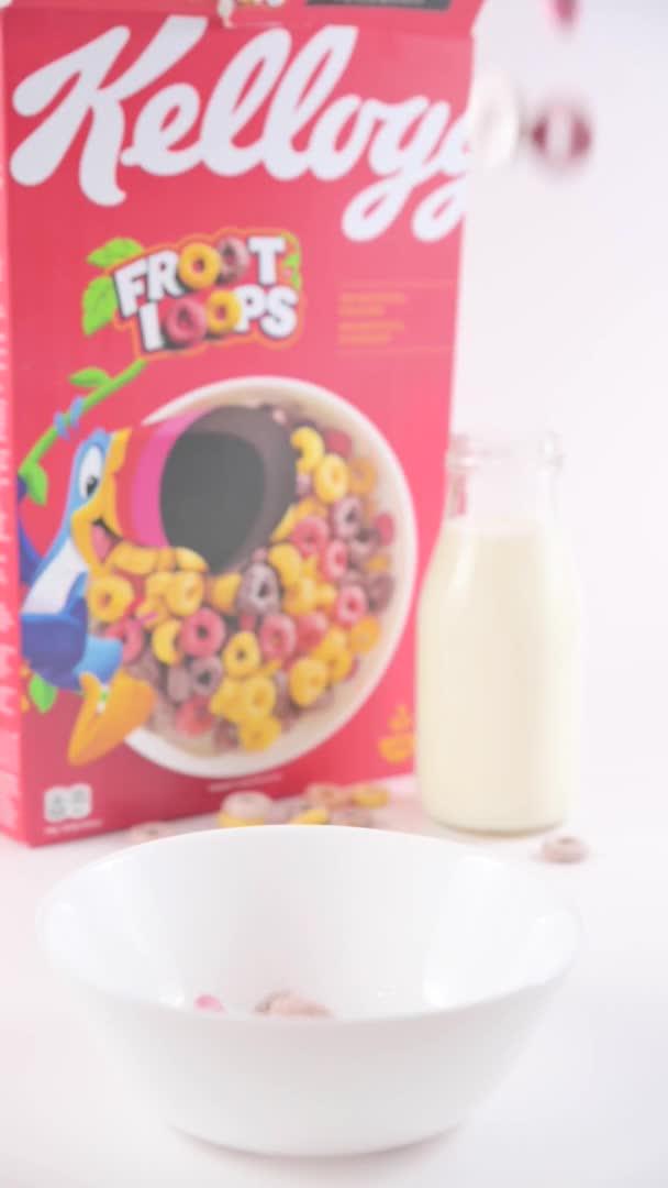 Colazione secca Kelloggs froot loop in una ciotola con latte. Anelli multicolori per la colazione dei bambini. Formato verticale, per smartphone e social network. Primo piano del cibo in un cucchiaio. — Video Stock