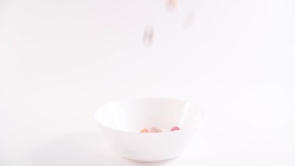 Colored cereals, dry breakfasts for children are poured into a bowl. — Wideo stockowe