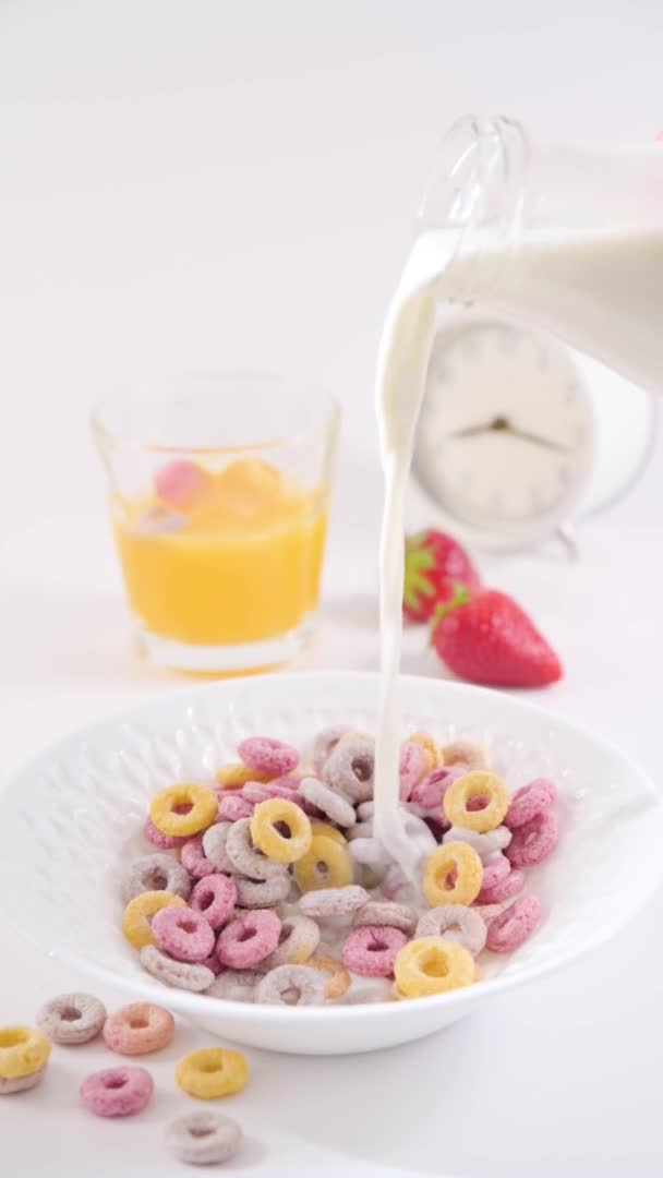 Trockenes Frühstück in einer Schüssel mit Milch. Bunte Ringe für das Kinderfrühstück. Vertikales Format, für Smartphones und soziale Netzwerke. Nahaufnahme von Lebensmitteln in einem Löffel. — Stockvideo