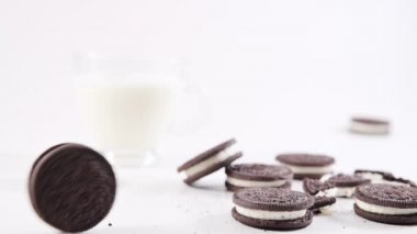 chocolate oreo cookies on a white background, roll cookies and a glass of milk. Popular childrens cookies with cream filling. 
