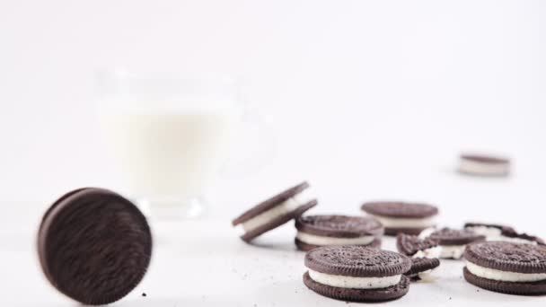 Oreo-Kekse aus Schokolade auf weißem Hintergrund, Rollkekse und ein Glas Milch. Beliebte Kinderkekse mit Sahnefüllung. — Stockvideo