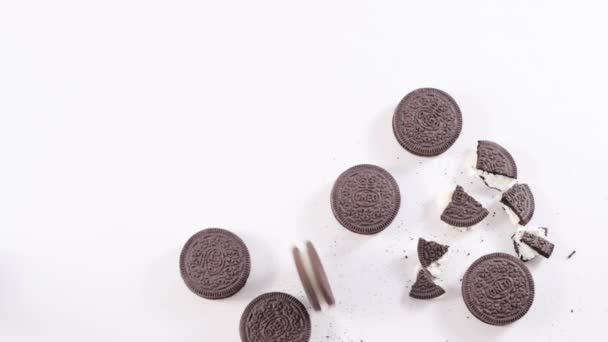 Oreo-Kekse aus Schokolade auf weißem Hintergrund, Rollkekse und ein Glas Milch. Beliebte Kinderkekse mit Sahnefüllung. — Stockvideo