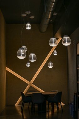 İçi avizeyle dolu oturma odasında. Koyu renklerde lüks ışıklandırma