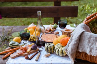Sonbahar pikniği. Sonbahar doğasında öğle yemeği için hazırlanmış bir masa, piknik. Hasat, sonbahar yemeği, şarap ve bardaklar. Açık hava toplantısı.