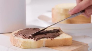 Çikolata ezmesi. Fındıklı çikolata taze ekmeğin üzerine yayılmış. Kahvaltıda tatlı tost. Yakından yiyecek dokusu. Klasik İtalyan tatlısı. Yüksek kalite 4k görüntü