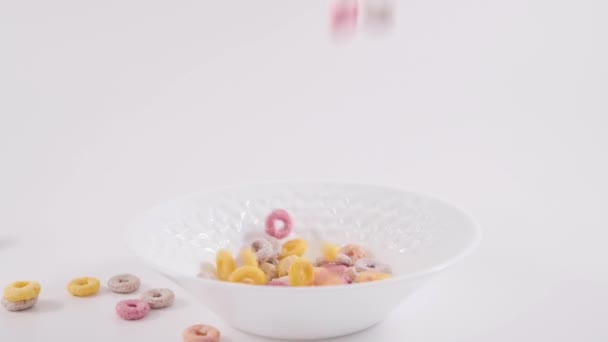 五颜六色的谷物和儿童干早餐被倒入碗中 健康食品 白底维生素均衡 — 图库视频影像