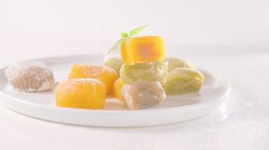 Geleneksel Japon tatlıları. Beyaz bir masanın üzerinde renkli mochi dondurması, böğürtlenli ve meyve dolgulu. Çocuklar için çocuklar günü tatili tatlısı. Yüksek kalite 4k görüntü
