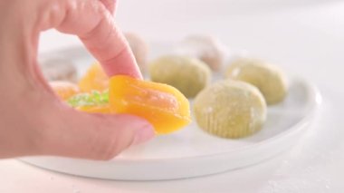 Geleneksel Japon tatlıları. Beyaz bir masanın üzerinde renkli mochi dondurması, böğürtlenli ve meyve dolgulu. Çocuklar için çocuklar günü tatili tatlısı. Yüksek kalite 4k görüntü