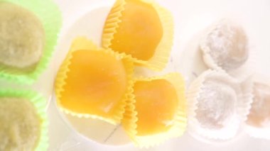 Geleneksel Japon tatlıları. Beyaz bir masanın üzerinde renkli mochi dondurması, böğürtlenli ve meyve dolgulu. Çocuklar için çocuklar günü tatili tatlısı. Yüksek kalite 4k görüntü