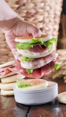 Tigelle veya crescentine ev yapımı, con prosciutto, salam, stracciatella liquida. Modena bölgesinin tipik İtalyan yemekleri, Emilia-Romagna. Prosciutto 4k dikey video ile doldurulmuş ince yuvarlak ekmekler