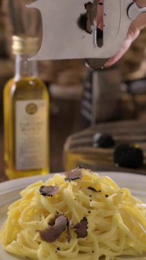 Eller, tagliatelle makarnasının üstüne kokulu siyah mantarı döker ve parçalar. Pahalı öğle yemeği, ev yapımı makarna, İtalya 'nın Lazo bölgesinde geleneksel. 4K görüntü. Sosyal ağlar için dikey