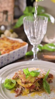 Pestoyla lazanya. İtalyan yemeği, hamur içinde ıspanak, ragu, et sosu, beşamel ve parmesan peyniri olan ev yapımı yeşil lazanya. İtalya 'da yemek atmosferi. Bir bardak şarap dolduruldu. dikey
