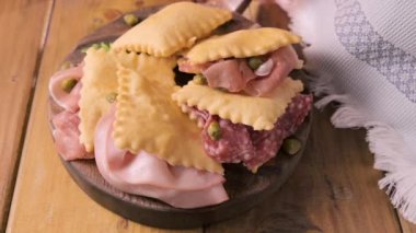 Hilal çiçeği. Emilia Romagna bölgesinin yiyeceği, kızarmış ekmek gnocco fritto ya da Crescentina. İtalya 'da aperatif veya aperatif. Prosciutto crudo, mortadella, Milano salamı, kapari, peynir ile Creshantina 