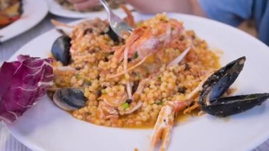 Italian pasta. Fregula with seafood. Traditional small round Sardinian pasta with shellfish, langoustine, mussels and vongole. in a restaurant. High quality FullHD footage