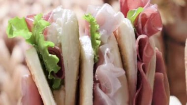 Tigelle veya crescentine ev yapımı, con prosciutto, salam, stracciatella liquida. Modena bölgesinin tipik İtalyan yemekleri, Emilia-Romagna. Prosciutto 4k dikey video ile doldurulmuş ince yuvarlak ekmekler