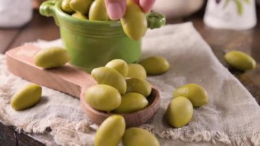 Large green olives in a cup on a wooden table. Italian olives, Sardenya and Greece harvest. High quality FullHD footage