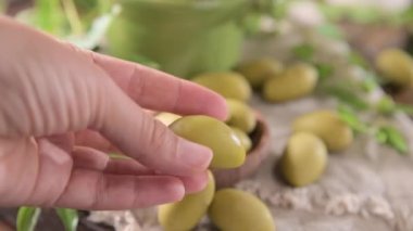 Large green olives in a cup on a wooden table. Italian olives, Sardenya and Greece harvest. Berry in hands close up