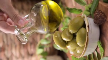 Large green olives in a cup on a wooden table. Italian olives, Sardenya and Greece harvest. Olive oil is poured on the berries, olive leaves in the frame. close-up