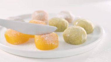 Geleneksel Japon tatlıları. Beyaz bir masanın üzerinde renkli mochi dondurması, böğürtlenli ve meyve dolgulu. Çocuklar için çocuklar günü tatili tatlısı. Yüksek kalite 4k görüntü
