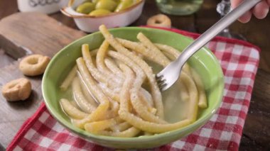 Italian Passatelli. Traditional Italian pasta cooked in broth. Typical Italian cuisine of the Puglia and Umbria region. High quality 4k footage., pasta on a fork with hot steam