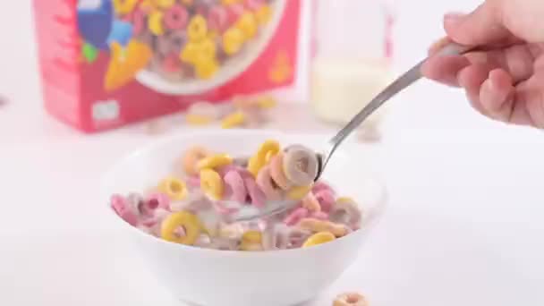 把早餐放在有牛奶的碗里烘干 儿童早餐用的五颜六色的戒指 用于智能手机和社交网络 一只勺子里的食物的特写 高质量的镜头 慢动作 — 图库视频影像