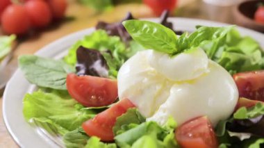 Domatesli salata, Burrata, fesleğen, zeytinyağı. Göbek adı Burratina. Puglia bölgesindeki İtalya 'nın güneyinden geleneksel peynir. Sıvı stracciatella dokusunun içinde yuvarlak yumuşak peynir 