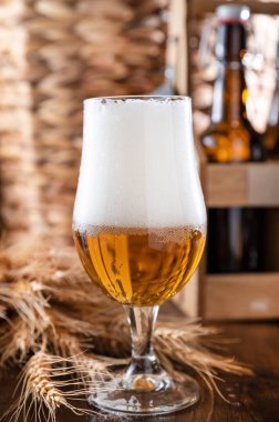 . Tahta bir masada bir bardak hafif bira. Bira köpüklü ve köpüklü bir bardağa doldurulur. Dikey. Sosyal medya ya da reklam için. bira dokusu. 