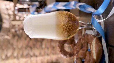 Oktoberfest. Tahta bir masada bir bardak hafif bira. Bira köpüklü ve köpüklü bir bardağa doldurulur. Sosyal medya veya reklam için dikey video. bira dokusu. 