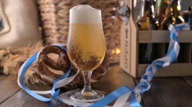 Oktoberfest birası. Köpüklü bira bir bardağa doldurulur ve Almanya 'daki Ekim Festivali' nin dekoru. Ve Bretzel - geleneksel Bavyera yemeği. Yüksek kaliteli FullHD görüntüler