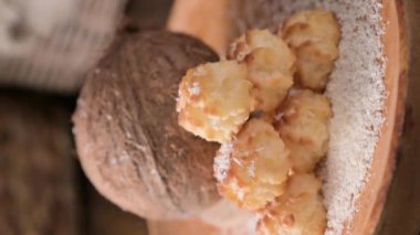 Coconut cookies. Homemade gluten free pastry with coconut. Small round sweets on a wooden table. High quality photo. real coconut are pouring. Vertical video