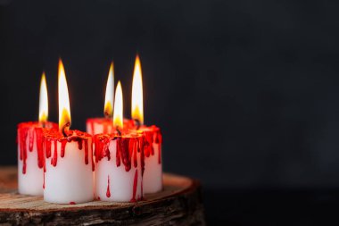 Karanlık arka planda kanlı mumlar yakmak. Kan damlaları gibi kırmızı balmumuyla kaplı beyaz mumlar. Kara büyü, büyücülük ritüeli. Cadılar Bayramı konsepti.