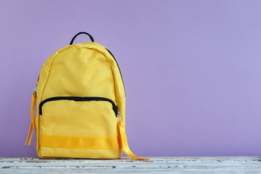 Boş mor bir arka planda, kopyalanmış sarı bir sırt çantası. Okul konseptine dönelim..