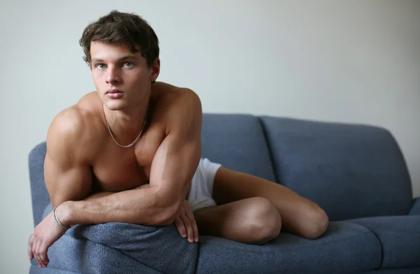 Jonge sexy man op een sofa — Stockfoto