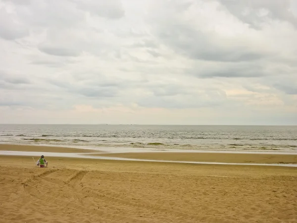 En kvinna som sitter på stranden — Stockfoto