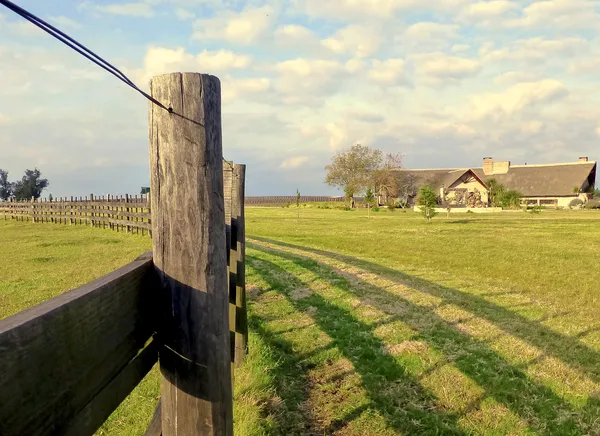 Ett staket och ett hus på landsbygden Royaltyfria Stockbilder