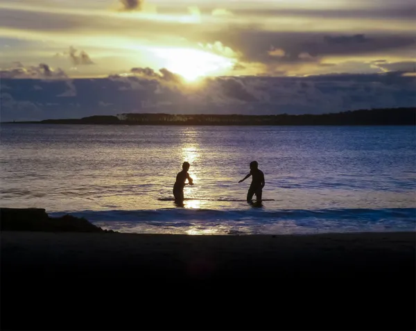 Bambini che giocano in mare al tramonto — Foto Stock